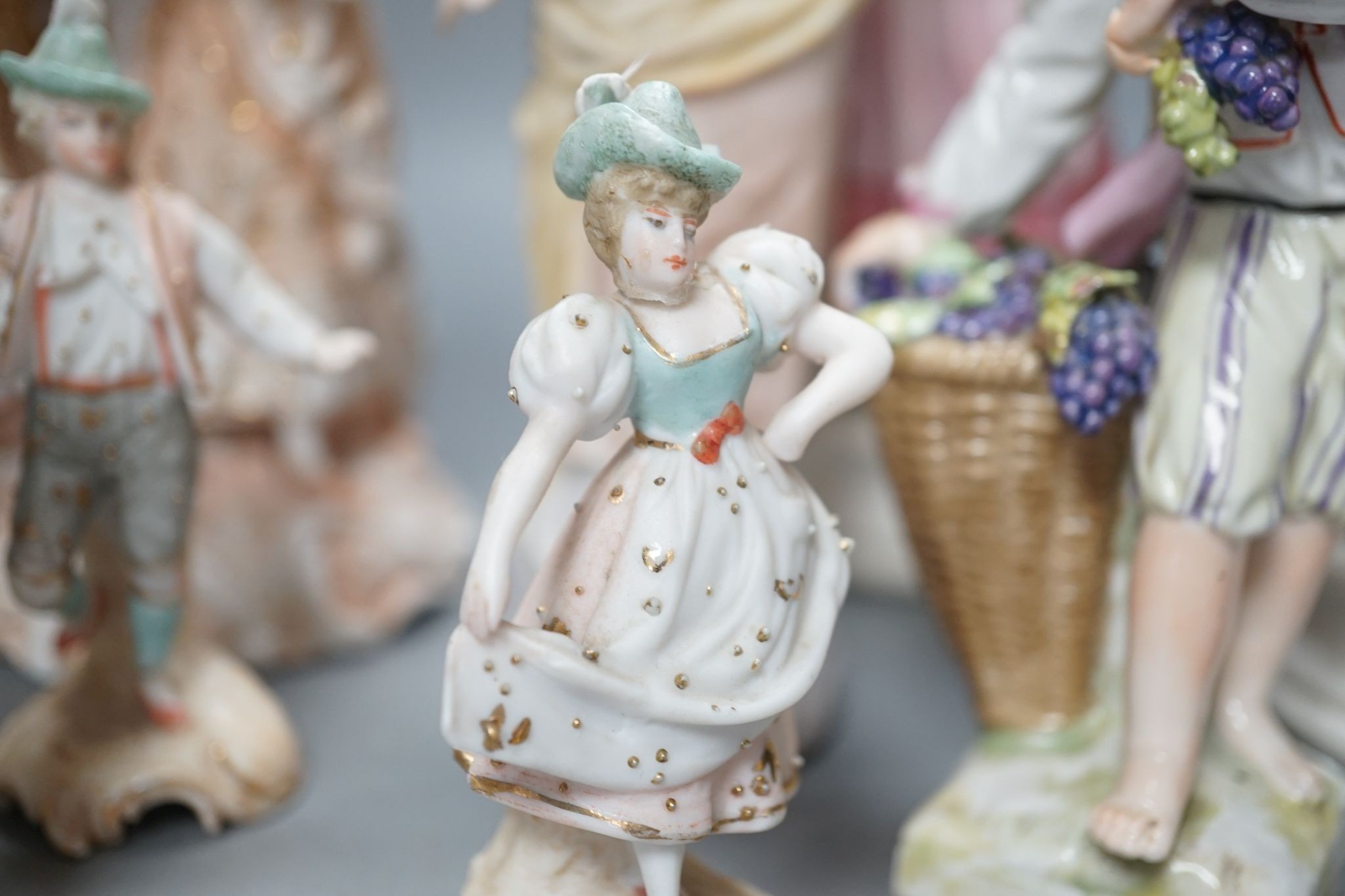 Ten French bisque figures and a Berlin figure of a grape picker, tallest 19cms high.